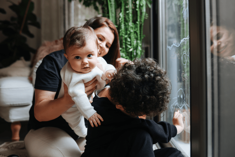 Young kids are hugging their mother in their new home.
