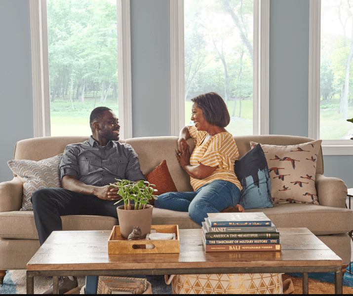 man and woman smile at each other on couch