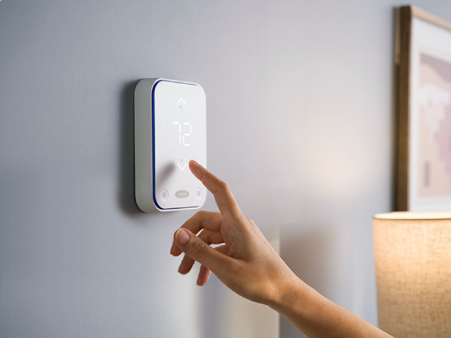 woman changing the settings on a Carrier smart thermostat